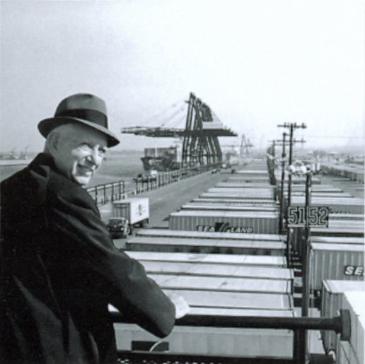 Malcom McLean, the inventor of the multimodal shipping container, pictured next to the Newark port full of shipping containers.