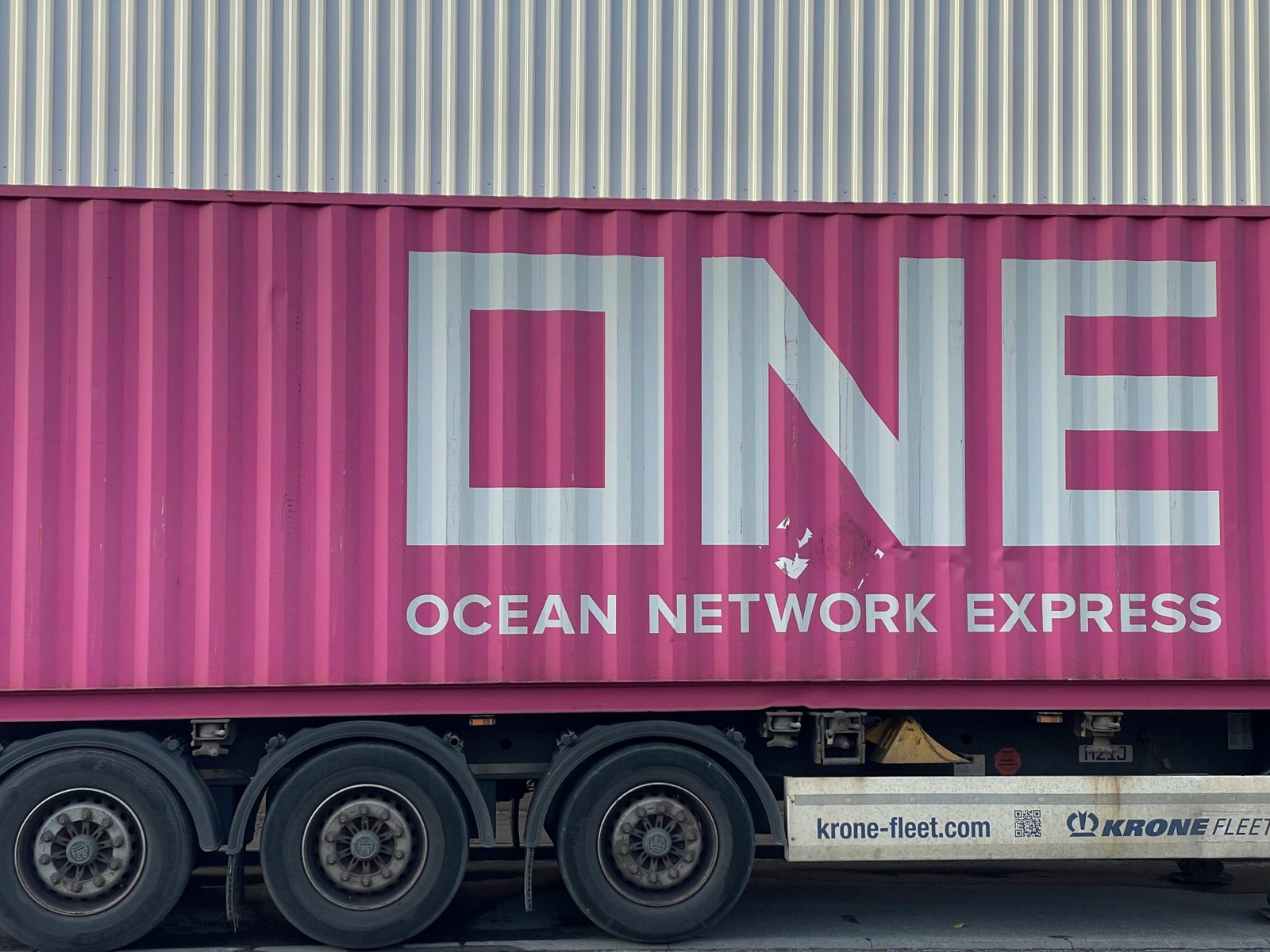 A pink multimodal shipping container on the back of a truck